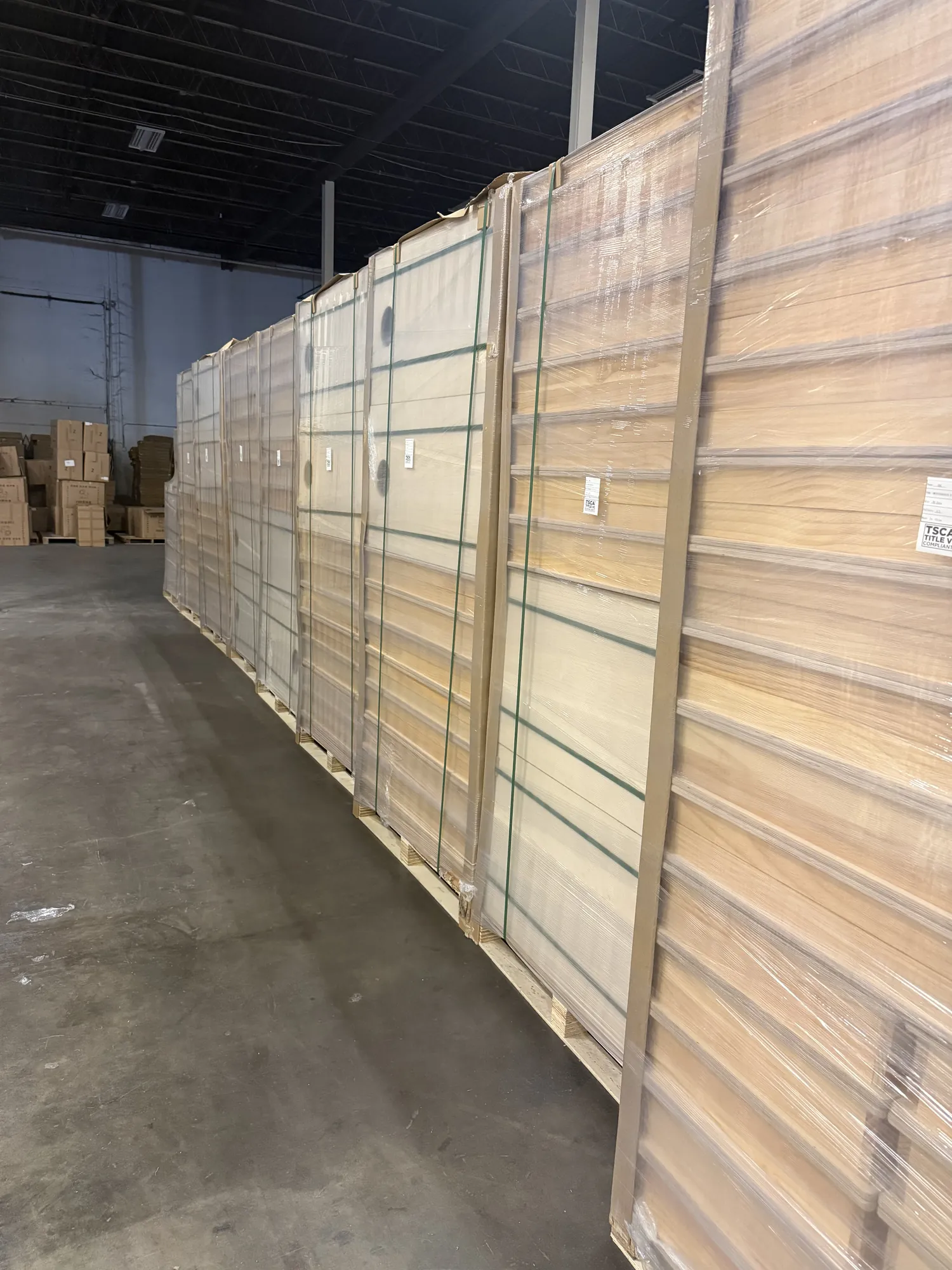 Rows of finished blank cornhole boards stacked and wrapped on pallets in the North Kansas City warehouse